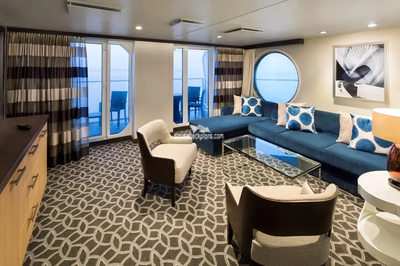 Quantum of the Seas suite living room with blue sofa and porthole