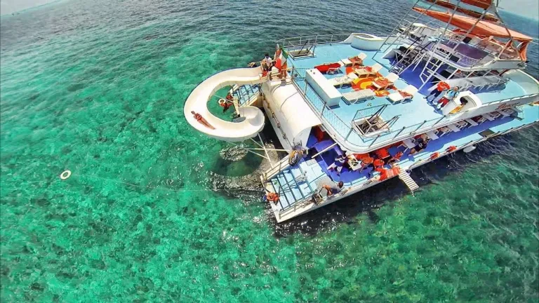 Aerial drone view of the party boat with guests swimming in crystal-clear water